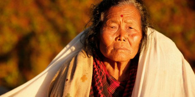 An elderly villager sit in the evening sun with a blanket in the destroyed village of Paslang near the epicenter of Saturday's massive earthquake in the Gorkha District of Nepal, Tuesday, April 28, 2015. Military operations continue Tuesday to reach the isolated areas following the powerful earthquake that has devastated the nation and killed at least 4,400 people, according to district official Surya Mohan Adhikari. (AP Photo/Wally Santana)
