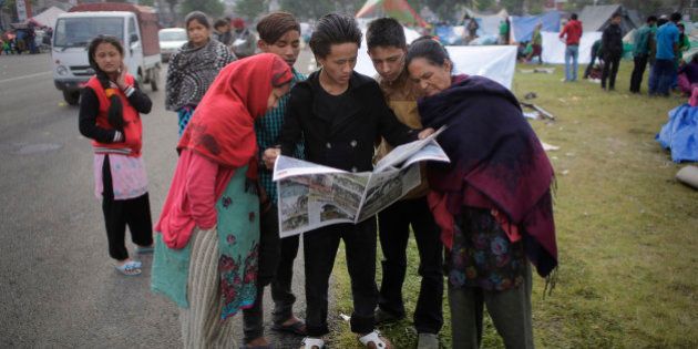 Survivors of Saturday's earthquake read the newspaper at a makeshift camp in Kathmandu, Nepal, Tuesday, April 28, 2015. A strong earthquake shook Nepalâs capital and the densely populated Kathmandu valley on Saturday. (AP Photo/Altaf Qadri)