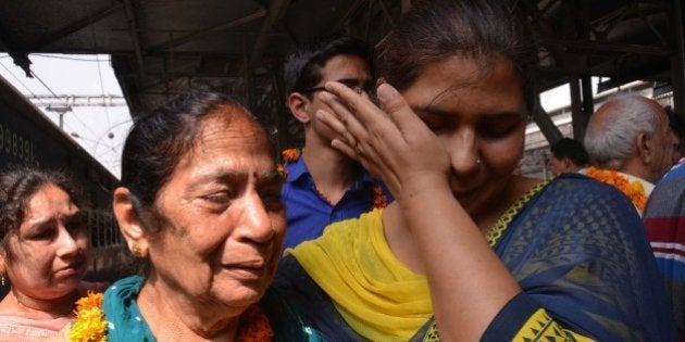 Indian resident Santosh (2L) is met by relatives after being evacuated following an earthquake in Nepal at the railway station in Amritsar on April 27, 2015. International aid groups and governments intensified efforts to get rescuers and supplies into earthquake-hit Nepal on April 26, 2015, but severed communications and landslides in the Himalayan nation posed formidable challenges to the relief effort. As the death toll surpassed 2,000, the US together with several European and Asian nations sent emergency crews to reinforce those scrambling to find survivors in the devastated capital Kathmandu and in rural areas cut off by blocked roads and patchy phone networks. AFP PHOTO/NARINDER NANU (Photo credit should read NARINDER NANU/AFP/Getty Images)