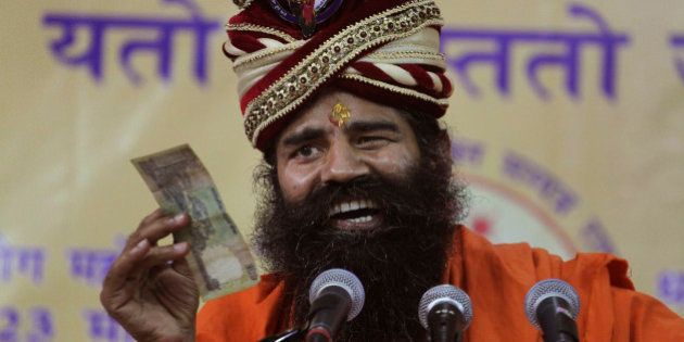 Indian yoga guru Baba Ramdev displays an Indian banknote as he makes fun of people running after money while addressing supporters in Ahmadabad, India, Monday, Feb. 3, 2014. Earlier in the day, addressing the media, Ramdev said he will launch a nationwide door-to-door campaign in support of the main opposition Bharatiya Janata Party(BJP)'s prime ministerial candidate Narendra Modi from March 1 in the run up to the 2014 parliament elections. (AP Photo/Ajit Solanki)