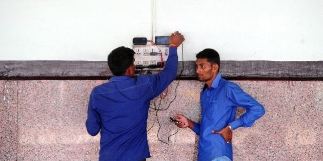 Indian passengers charge their mobile phones at Allahabad Junction in Allahabad on February 26, 2015. India said it would spend 137 billion dollars to modernise its crumbling railways, pledging to restore the 'backbone' of the country to its former glory -- and introduce yoga lessons for stressed-out staff. AFP PHOTO / SANJAY KANOJIA (Photo credit should read Sanjay Kanojia/AFP/Getty Images)