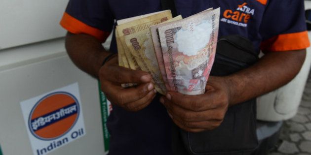 An Indian petrol pump employee counts Indian currency in Siliguri on August 28, 2013. India's rupee slumped nearly four percent to a fresh record low against the dollar as concerns about a US-led military strike against Syria compounded deepening domestic economic woes. The Indian unit, which lost three percent on August 27, was down 2.46 percent at 67.87 rupees to the dollar in afternoon trade after plunging 3.84 percent at one point to 68.74 rupee AFP PHOTO/Diptendu DUTTA (Photo credit should read DIPTENDU DUTTA/AFP/Getty Images)