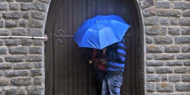 An Indian couple take shelter in a doorway of a church during heavy rainfall in Shimla on February 25, 2015. AFP PHOTO/STR (Photo credit should read STRDEL/AFP/Getty Images)
