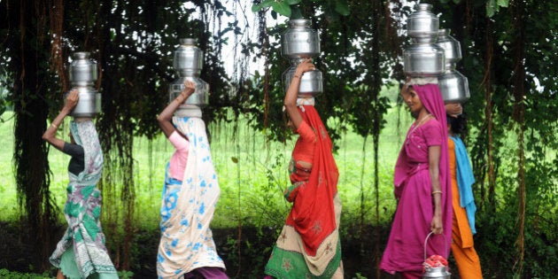 Indian women carry drinking water utensils at Tilakwada village near Sardar Sarovar Narmada Dam on Narmada river at Kevadia Colony, some 175 kms from Ahmedabad on August 29, 2011. The dam is one of India's most controversial dam projects and its environmental impact and net costs and benefits are widely debated. AFP PHOTO / Sam PANTHAKY (Photo credit should read SAM PANTHAKY/AFP/Getty Images)