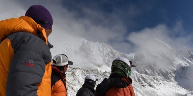 Nepalese Sherpas look up towards an area where an avalanche triggered by an earthquake occurred at Everest Base Camp on April 26, 2015, a day after the avalanche triggered by an earthquake devastated the camp. Rescuers in Nepal are searching frantically for survivors of a huge quake on April 25, that killed nearly 2,000, digging through rubble in the devastated capital Kathmandu and airlifting victims of an avalanche at Everest base Camp. The bodies of those who perished lie under orange tents. AFP PHOTO/ROBERTO SCHMIDT (Photo credit should read ROBERTO SCHMIDT/AFP/Getty Images)