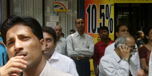 People watch a screen displaying the share prices outside the building of the Bombay Stock Exchange in Mumbai, India, Monday, April 2, 2007. Indian shares fell sharply in early trade Monday, spooked by fresh moves from the country's central bank to tighten monetary policy and increase lending rates that could likely slow economic growth. The 30-share Sensex of the Bombay Stock Exchange plunged 394 points, 3 percent, to 12,678 points in early trading. On the broader National Stock Exchange, the 50-company S&P Nifty index fell 3.2 percent to 3,700 points. (AP Photo/Gautam Singh)