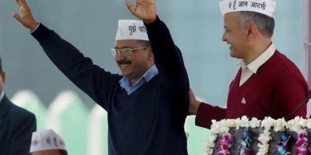 Aam Aadmi Party (AAP) president Arvind Kejriwal (L) greets his supporters as fellow Minister Manish Sisodia (R) congratulates him during his swearing-in ceremony as Delhi chief minister in New Delhi on February 14, 2015. Arvind Kejriwal promised to make Delhi India's first corruption-free state and end what he called its 'VIP culture' as he was sworn in as chief minister before a huge crowd of cheering supporters . AFP PHOTO / PRAKASH SINGH (Photo credit should read PRAKASH SINGH/AFP/Getty Images)