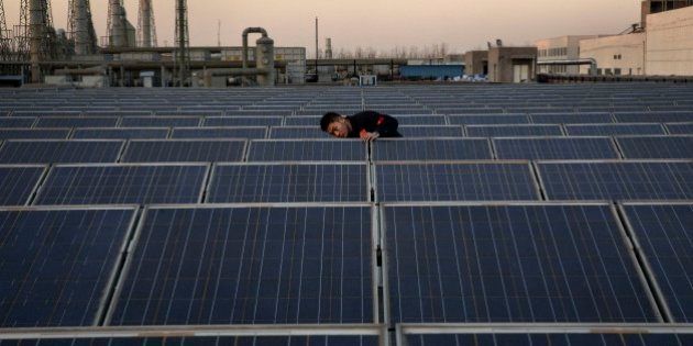 BAODING, CHINA - DECEMBER 4: A technician from Yingli Solar checks a solar panel used to produce energy for lighting, on the roof at the company's headquarters on December 4, 2014 in Baoding, Hebei Province. China is the largest energy consumer in the world with the main source of its electricity generated by coal, but in moves to reduce carbon emissions China is also setting records for installing solar panels and generating solar power. (Photo by Kevin Frayer/Getty Images)