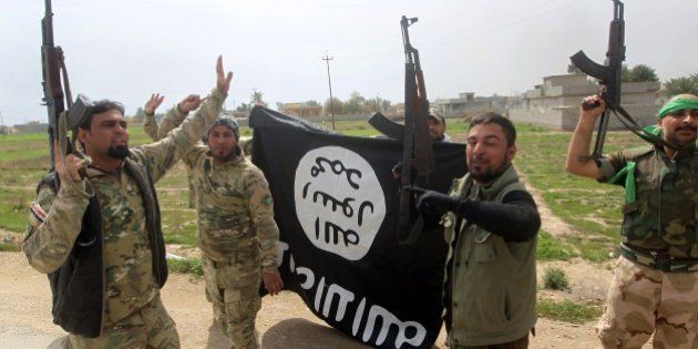 Members of the Iraqi paramilitary Popular Mobilisation units celebrate with a flag of the Islamic State (IS) group after retaking the village of Albu Ajil, near the city of Tikrit, from the jihadist group, on March 9, 2015. Some 30,000 Iraqi soldiers, police and the increasingly influential paramilitary Popular Mobilisation units, which are dominated by Shiite militias, have been involved in a week-old operation to recapture Tikrit, one of the jihadists' main hubs since they overran large parts of Iraq nine months ago. AFP PHOTO / AHMAD AL-RUBAYE (Photo credit should read AHMAD AL-RUBAYE/AFP/Getty Images)