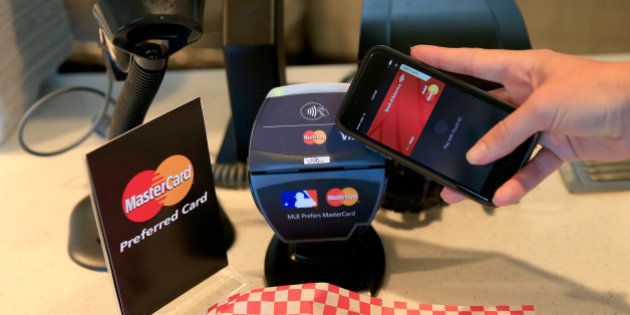 SAN FRANCISCO, CA - OCTOBER 24: A fan uses MasterCard with Apple Pay to pay for garlic fries before Game Three of the 2014 World Series at AT&T Park on October 24, 2014 in San Francisco, California. (Photo by Rob Carr/Getty Images for MasterCard)