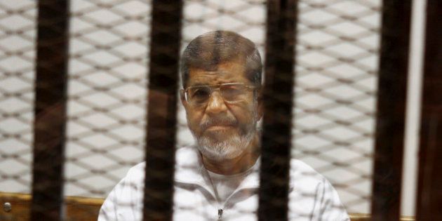 FILE - In this May 8, 2014 file photo, Egypt's ousted Islamist President Mohammed Morsi sits in a defendant cage in the Police Academy courthouse in Cairo, Egypt. An Egyptian court sentenced ousted President Mohammed Morsi to death, Saturday, May 16, 2015, over a 2011 mass prison break.. (AP Photo/Tarek el-Gabbas, File)