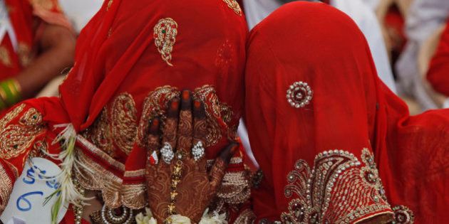 An Indian bride whispers to another during a mass marriage ceremony in Ahmadabad, India, Saturday, March 21, 2015. 112 Muslim couples from impoverished families tied the knot in a single ceremony organized by a social organization. (AP Photo/Ajit Solanki)