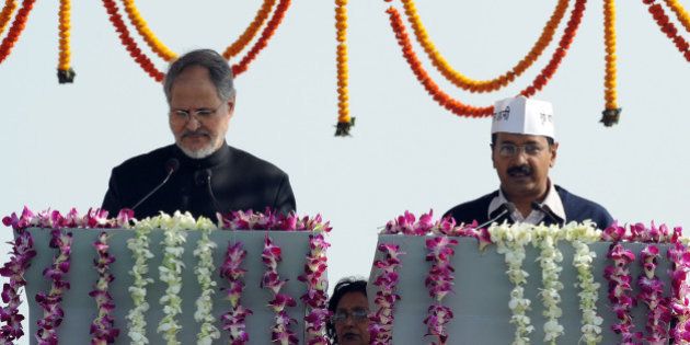 Anti-corruption champion and Aam Admi (Common Man) Party Leader Arvind Kejriwal (R) takes his oath of office as Chief Minister of India's national capital region from Delhi's Lt. Governor Najeeb Jung (L) at a ceremony in New Delhi on December 28, 2013, in what supporters hoped would mark a turning point in the nation's graft-ridden politics. Cheers rang out as Kejriwal, who arrived for the ceremony on the city's subway, took the oath office in front of tens of thousands of supporters assembled in a Delhi park wearing white caps emblazoned with Kejriwal's slogan, 'I am a common man'. AFP PHOTO/RAVEENDRAN (Photo credit should read RAVEENDRAN/AFP/Getty Images)