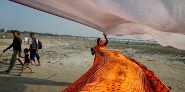 An Indian Hindu woman dries saris after taking ritualistic holy dip in the river Ganges, in Allahabad, India, Tuesday, Sept. 23, 2014. Allahabad, on the confluence of the rivers Ganges and Yamuna is one of Hinduism's important centers. (AP Photo/Rajesh Kumar Singh)