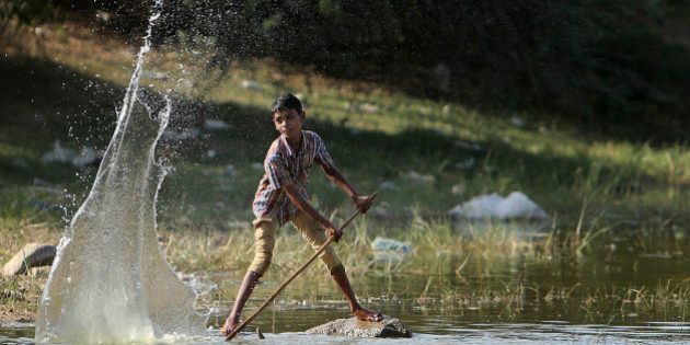 An Indian boy plays with water at a pond on a hot summer day in Hyderabad, India, Sunday, May 24, 2015. About 230 people have died since mid-April in a heat wave sweeping two southeast Indian states, Andhra Pradesh and Telangana, officials said Saturday. Day temperatures in Telangana's Khammam district soared to more than 48 degrees Celsius (118 Fahrenheit) on Saturday. (AP Photo/Mahesh Kumar A.)