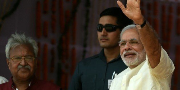 Indian Prime Minister Narendra Modi gestures to the crowd as he arrives at a rally venue in Mathura on May 25, 2015. Prime Minister Narendra Modi has vowed to improve the lot of India's beleaguered farmers, promising non-stop power and better irrigation, as he battles to win approval for a controversial land bill. At a mass rally to mark the first anniversary of his inauguration, Modi told thousands of supporters that he had attacked corruption in his first 12 months in office and ended the 'looting' of the country. AFP PHOTO/MONEY SHARMA (Photo credit should read MONEY SHARMA/AFP/Getty Images)