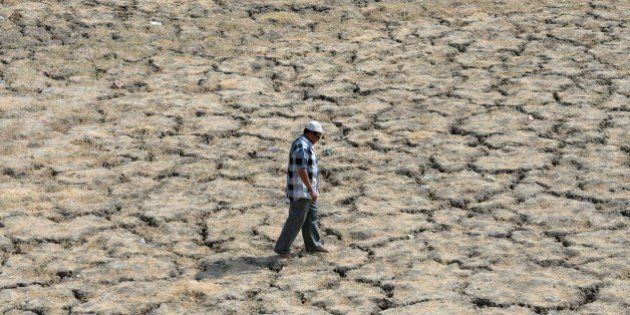 This photo taken on May 28, 2015 shows an Indian man walking across the dried-out bed of Lake Ahmad Sar as extreme heat conditions prevail in Ahmedabad. Hospitals in India battled May 28 to treat victims of a blistering heatwave that has claimed more than 1,700 lives in just over a week -- the highest number recorded in two decades. AFP PHOTO / Sam PANTHAKY (Photo credit should read SAM PANTHAKY/AFP/Getty Images)