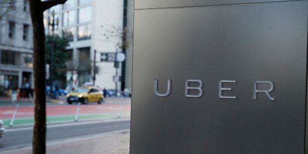 In this photo taken Tuesday, Dec. 16, 2014, a taxi on Market Street goes past the headquarters of Uber in San Francisco. (AP Photo/Eric Risberg)