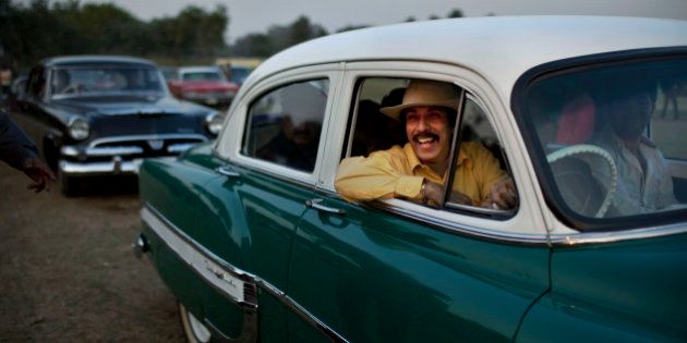 Indian businessman Ahsok Kaicker smiles as he drives in his vintage 1953 Chevrolet Bel-Air during a display in a break at the Cavalry Gold Cup Polo match at the Jaipur Polo Grounds in New Delhi, India, Sunday, Dec. 12, 2010. (AP Photo/Kevin Frayer)