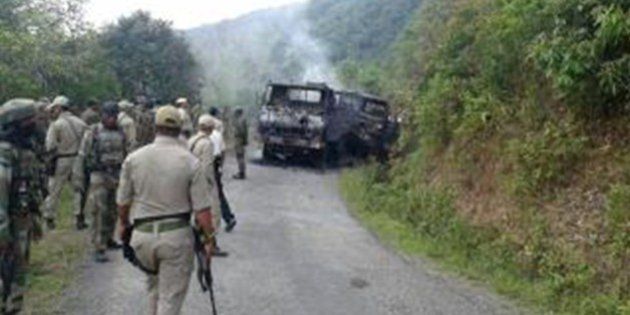 This photograph taken on June 4, 2015 shows Indian security personnel and smoldering vehicle wreckage at the scene of an attack on a military convoy in a remote area of Chandel district, about 120 kilometres (75 miles) southwest of northeastern India's Manipur's state capital Imphal. Heavily armed rebels in India's restive northeast killed at least 20 troops on June 4, police said, in one of the area's worst such attacks in years. AFP PHOTO (Photo credit should read STR/AFP/Getty Images)