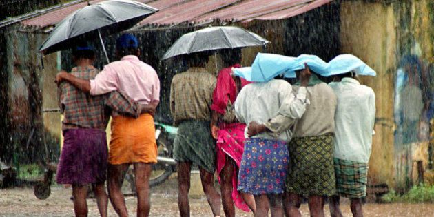 Fishermen walk under umbrellas and plastic sheets in the rain at the Cochin Harbor in Cochin, in the southern Indian state of Kerala, Wednesday, June 25, 2003. Kerala has been witnessing heavy southwest monsoons for the past week. (AP Photo)