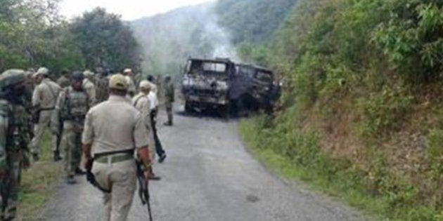 This photograph taken on June 4, 2015 shows Indian security personnel and smoldering vehicle wreckage at the scene of an attack on a military convoy in a remote area of Chandel district, about 120 kilometres (75 miles) southwest of northeastern India's Manipur's state capital Imphal. Heavily armed rebels in India's restive northeast killed at least 20 troops on June 4, police said, in one of the area's worst such attacks in years. AFP PHOTO (Photo credit should read STR/AFP/Getty Images)