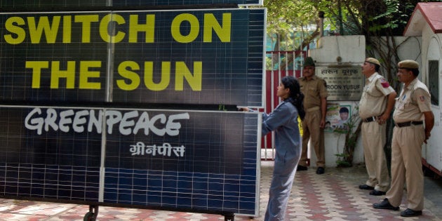 Indian policemen look on as a Greenpeace activist blocks the entry to the residence of Delhi's Power Minister Haroon Yusuf with a bank of solar panels in New Delhi on May 15, 2013. Greenpeace activists demanded that Delhi Government should take steps to improve its performance on the use of renewable source of energy to deal with capital's power crisis. AFP PHOTO/ Prakash SINGH (Photo credit should read PRAKASH SINGH/AFP/Getty Images)