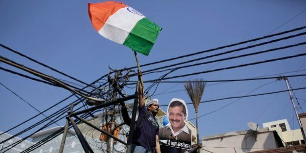 A supporter of the Aam Aadmi Party, or Common Manâs Party, waves the Indian flag next to a portrait of its leader Arvind Kejriwal and party symbol, broom, as he celebrates party's victory in New Delhi, India, Tuesday, Feb. 10, 2015. The upstart anti-corruption party has won a smashing victory in elections to install a state government in India's capital, officials said Tuesday, dealing a huge blow to Prime Minister Narendra Modi's Hindu nationalist party. Hindi below the portrait reads,