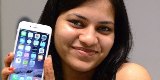An Indian customer poses with her brand new Apple iPhone 6 at the Unicorn Infosolutions Apple Premium Reseller store in Ahmedabad early on October 17, 2014. Apple launched the iPhone 6 and iPhone 6 Plus smartphones in India at midnight on October 17. AFP PHOTO / Sam PANTHAKY (Photo credit should read SAM PANTHAKY/AFP/Getty Images)