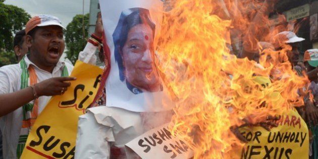 Congress supporters shout anti-Bharatiya Janata Party (BJP) slogans as they burn effigies of External Affairs Minister, Sushma Swaraj and former cricket administrator, Lalit Modi during a protest in Kolkata on June 17, 2015. Congress ramped up its demand for the resignation of Rajasthan chief minister, Vasundhara Raje and External Affairs Minister, Sushma Swaraj a day after controversial former Indian Premier League (IPL) boss Lalit Modi claimed they helped him with his travel papers in Britain. AFP PHOTO/ Dibyangshu SARKAR (Photo credit should read DIBYANGSHU SARKAR/AFP/Getty Images)
