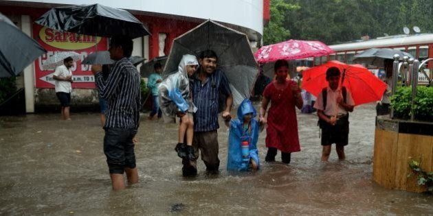 Indians walk through a flooded street during rain showers in Mumbai on July 23, 2013. The Mumbai city witnessed heavy rains on Tuesday, resulting in heavy traffic jams and disrupting train services. The monsoon season, which runs from June to September, accounts for about 80 percent of India's annual rainfall, vital for a farm economy which lacks adequate irrigation facilities. AFP PHOTO/ PUNIT PARANJPE (Photo credit should read PUNIT PARANJPE/AFP/Getty Images)