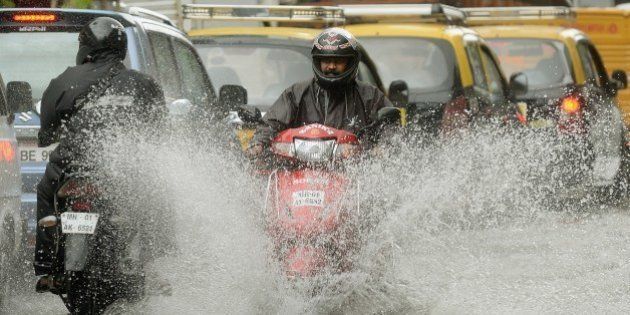 An Indian motorcyclist rides along a flooded street after heavy rain in Mumbai on July 16, 2014. The monsoon rains, which usually hit India from June to September, are crucial for farmers whose crops feed hundreds of millions of people. AFP PHOTO/ PUNIT PARANJPE (Photo credit should read PUNIT PARANJPE/AFP/Getty Images)