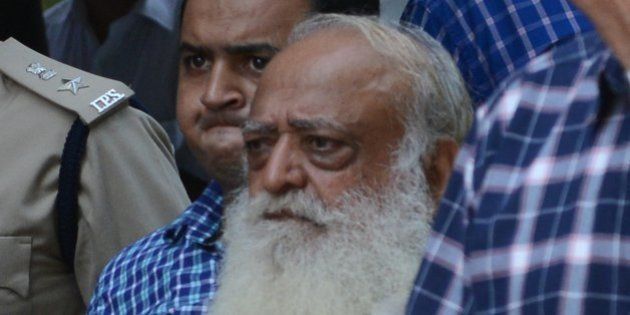 Indian spiritual guru Asaram Bapu (C, in white) is escorted by state police as he arrives at a local court in Gandhinagar, some 30 kms. from Ahmedabad, on October 15, 2013. The court ordered the spiritual guru to be under police custody until October 19 in connection with a sexual assault case. AFP PHOTO / Sam PANTHAKY (Photo credit should read SAM PANTHAKY/AFP/Getty Images)