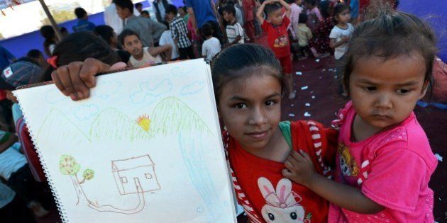 A Nepalese child holds up a drawing at a relief camp for survivors of the Nepal earthquake in Kathmandu on May 23, 2015. Nearly 8,500 people have now been confirmed dead in the disaster, which destroyed more than half a million homes and left huge numbers of people without shelter with just weeks to go until the monsoon rains. AFP PHOTO / ISHARA S. KODIKARA (Photo credit should read Ishara S.KODIKARA/AFP/Getty Images)