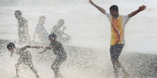 Indian youths play in breaking waves on the seafront during high tide in Mumbai on June 17, 2015. AFP PHOTO/ PUNIT PARANJPE (Photo credit should read PUNIT PARANJPE/AFP/Getty Images)