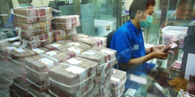 Employees of BNI bank, an Indonesian state-owned bank, prepare rupiah banknotes for their ATMs and branch offices in Jakarta on April 1, 2015. Indonesia's Central Bank had warned that the risk of losses due to the currency exchange rate of private and state-owned companies' foreign debts are still high and continue to haunt throughout 2015. AFP PHOTO / Bay ISMOYO (Photo credit should read BAY ISMOYO/AFP/Getty Images)