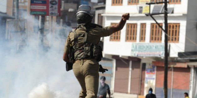 An Indian security personnel throws a rock towards Kashmiri protestors during clashes in Srinagar on April 17, 2015. Police arrested a prominent separatist leader in Indian-administered Kashmir on April 17, 2015 after he led a rally where supporters waved Pakistani flags and chanted pro-Pakistan slogans. Kashmir has been rocked by violent protests after the brother of a top rebel leader was killed by the army near the town of Tral in the south of the Kashmir valley. AFP PHOTO / Tauseef MUSTAFA (Photo credit should read TAUSEEF MUSTAFA/AFP/Getty Images)