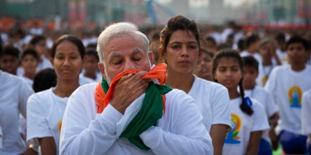 Indian Prime Minister Narendra Modi wipes his sweat with a scarf made in the colors of Indian tricolor as he performs yoga along with thousands of Indians on Rajpath, in New Delhi, India, Sunday, June 21, 2015. Millions of yoga enthusiasts are bending their bodies in complex postures across India as they take part in a mass yoga program to mark the first International Yoga Day.(AP Photo/Saurabh Das)