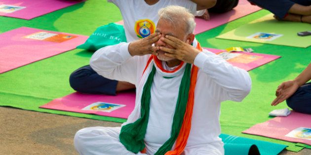 Indian Prime Minister Narendra Modi, performs breathing exercise during yoga along with thousands of Indians on Rajpath, in New Delhi, India, Sunday, June 21, 2015. Millions of yoga enthusiasts are bending their bodies in complex postures across India as they take part in a mass yoga program to mark the first International Yoga Day. (AP Photo/ Manish Swarup)