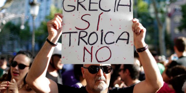 A man holds a banner during a pro Greece demonstration at the European Union Office in Barcelona, Spain, Monday, June 29, 2015. Spain's economy minister has said a Greek debt deal is still reachable, although Spain's benchmark Ibex stock index slid nearly 4 percent Monday morning. The banner reads in Spanish: