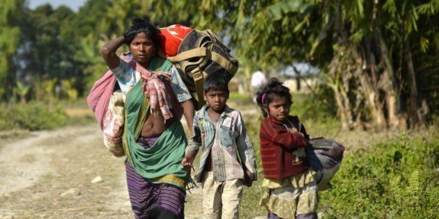 Indian villagers carry their belongings as they flee from the village of Tenganala in Sonitpur District, some 250kms east of Guwahati on December 24, 2014, after their relatives were killed by militants. Violence in the restive Indian state of Assam has killed 68 people including 12 children, authorities said, as separatist rebels dramatically intensified a long-running campaign in the tea-growing area. Heavily armed militants launched a series of coordinated attacks in rural Assam late December 22, pulling villagers from their homes and shooting them at point-blank range, witnesses said. AFP PHOTO/STR (Photo credit should read STRDEL/AFP/Getty Images)