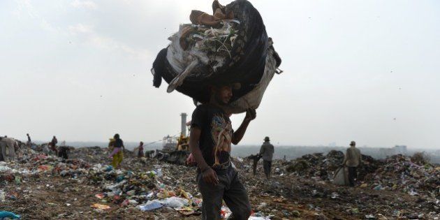 An Indian rag picker carries a sack of sorted recyclable materials at the Ghazipur landfill site in the east of New Delhi on August 19, 2014. The population of New Delhi, which is predicted to reach close to 21 million by the year 2015, generates 8,000 tons of garbage per day. The trash is not separated between organic and inorganic materials - everything from leftover food to batteries and beverage cans goes into Indian bins - hurting efficiency and raising toxic emissions. AFP PHOTO/Chandan Khanna (Photo credit should read Chandan Khanna/AFP/Getty Images)