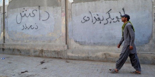 A Pakistani man walks past a wall graffiti reading 'Abu Bakr al-Baghdadi', leader of the Islamic State (IS) jihadist group in Iraq, in Quetta on November 24, 2014. The Islamic State organisation is starting to attract the attention of radicals in Pakistan and Afghanistan, long a cradle for Islamist militancy, unnerving authorities who fear a potential violent contagion. AFP PHOTO/Banaras KHAN (Photo credit should read BANARAS KHAN/AFP/Getty Images)