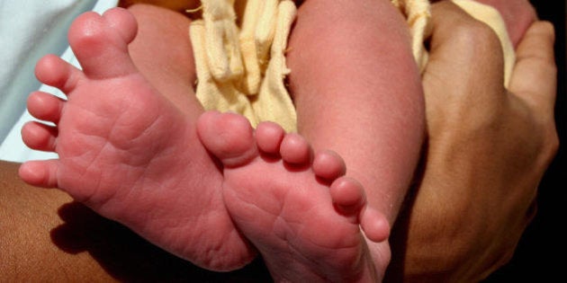 Ahmedabad, INDIA: Indian infant boy, Lakshya who was born with a total of 25 fingers and toes, nestles in his mother's arms in Nadidad, some 60 kms south of Ahmedabad, 11 December 2006. Lakshya was born on 03 December 2006 with six fingers on each hand, six toes on the right foot and seven on the left foot. AFP PHOTO/Sam PANTHAKY (Photo credit should read SAM PANTHAKY/AFP/Getty Images)