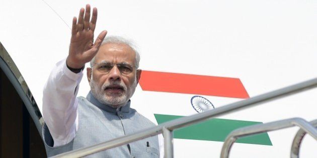 Indian Prime Minister, Narendra Modi waves as he leaves the plane on his arrival at the Hazrat Shahjalal International Airport in Dhaka on June 6, 2015. India's prime minister arrived in Bangladesh to seal a land pact which will finally allow tens of thousands of people living in border enclaves to choose their nationality after decades of stateless limbo. AFP PHOTO/ Munir uz ZAMAN (Photo credit should read MUNIR UZ ZAMAN/AFP/Getty Images)