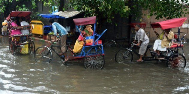 Indian cycle rickshaw drivers ferry commuters through floodwaters on a street of New Delhi on July 9, 2015, after heavy monsoon rainfall. AFP PHOTO/MONEY SHARMA (Photo credit should read MONEY SHARMA/AFP/Getty Images)