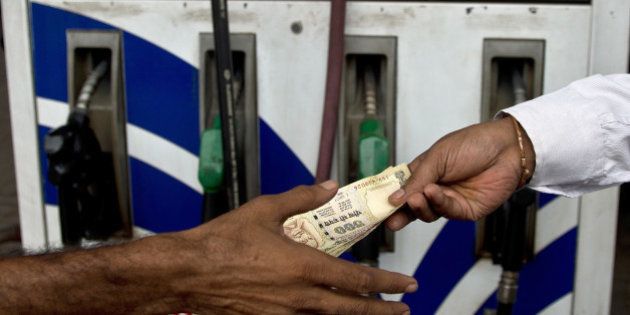 An Indian comsumer (R) pays a petrol-pump attendant in New Delhi on July 30, 2013. India's central bank kept its benchmark interest rates unchanged on July 30, ignoring demands for a cut as it seeks to defend the ailing rupee from a further devaluation. AFP PHOTO/MANAN VATSYAYANA (Photo credit should read MANAN VATSYAYANA/AFP/Getty Images)