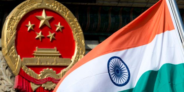 An Indian national flag is flown next to the Chinese national emblem during a welcome ceremony for visiting Indian Prime Minister Manmohan Singh, outside the Great Hall of the People in Beijing Wednesday, Oct. 23, 2013. China and India signed a confidence-building accord Wednesday to cooperate on border defense following a standoff between armed forces of the two Asian giants in disputed Himalayan territory earlier this year. (AP Photo/Andy Wong)