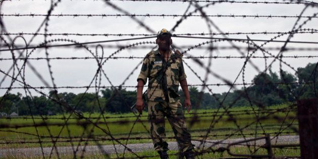 LALMONIRHAT DISTRICT, BANGLADESH - JULY 10: A member of the Indian BSF stands across from the India/Bangladesh border fence July 10, 2015 in Lalmonirhat District, Bangladesh. The India Bangladesh enclaves, also known as the chitmahals, are 162 parcels of land, each of which happens to lie on the wrong side of the India/Bangladesh border. There are 111 such Indian enclaves in Bangladesh and 51 Bangladeshi enclaves in India. On June 6th Bangladesh and India came to an agreement to let residents choose which country they want to belong to, and on July 31st these enclaves will dissolve into the country already surrounding them. For decades, these people have been stateless. Both the Bangladesh and Indian governments have refused to take responsibility for the enclave residents. Their villages do without public services, they cannot vote, and parents must forge documents to send their children to schools. Until the Enclaves Exchange Coordination Committee came to their enclaves this month, most Indian enclaves residents had never laid eyes on an Indian national before. (Photo by Shazia Rahman/Getty Images)