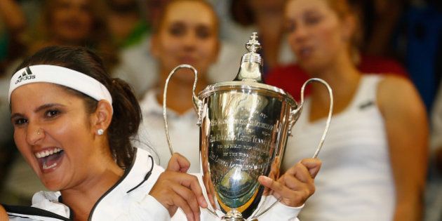 LONDON, ENGLAND - JULY 11: Sania Mirza of India and Martina Hingis of Switzerland celebrate with the trophy after winning the Final Of The Ladies' Doubles against Ekaterina Makarova of Russia and Elena Vesnina of Russia during day twelve of the Wimbledon Lawn Tennis Championships at the All England Lawn Tennis and Croquet Club on July 11, 2015 in London, England. (Photo by Julian Finney/Getty Images)